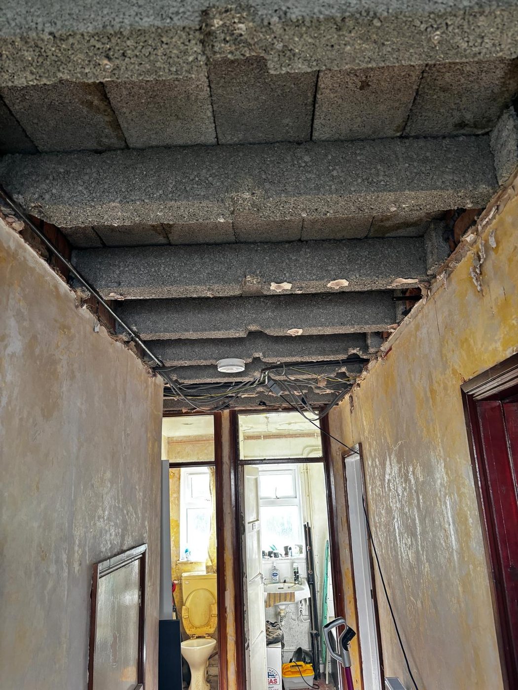 A corridor ceiling open with new cable runs between joists